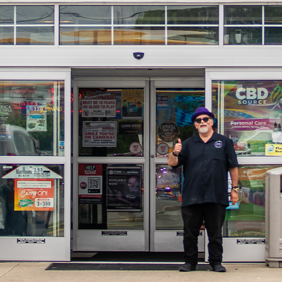Staff Member Giving Thumbs Up Outside Smoker's Choice Store Entrance
