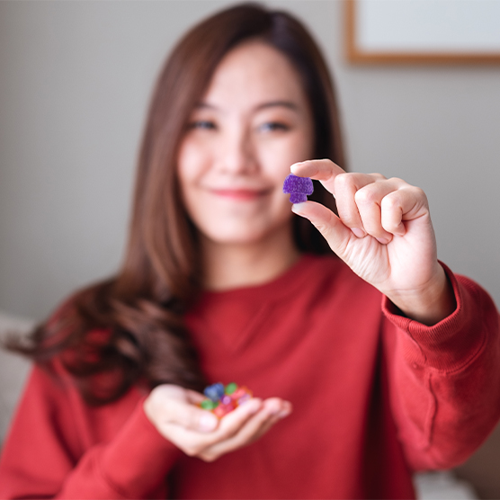 woman holding a purple mushroom gummy candy